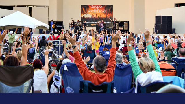 Patrons with arms raised in the air at Sunday on the Waterfront concert-Photo by Pat McMenamin