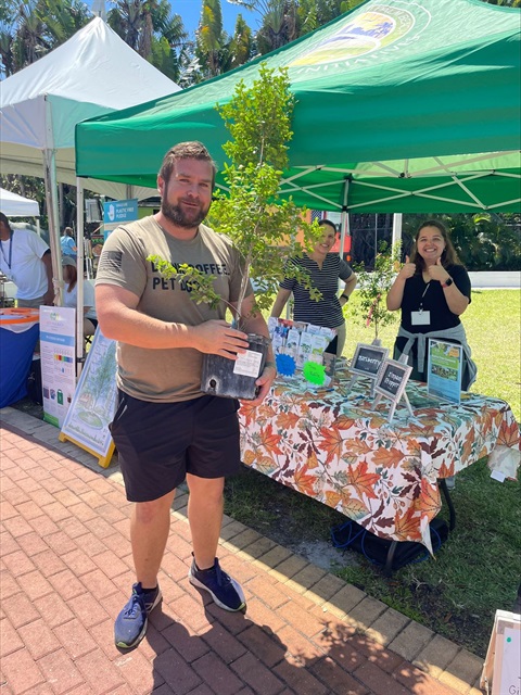 Man holding tree at giveaway tent outside